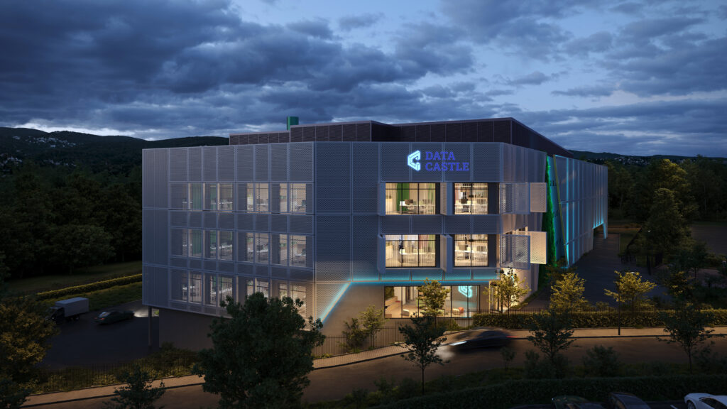 Modern data center building illuminated at night, with a dramatic sky and surrounding landscape.